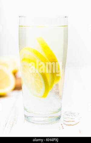 Ein Becherglas und einen Krug kalten Limonade auf einem weißen Hintergrund Holz umgeben von Zitronen Stockfoto