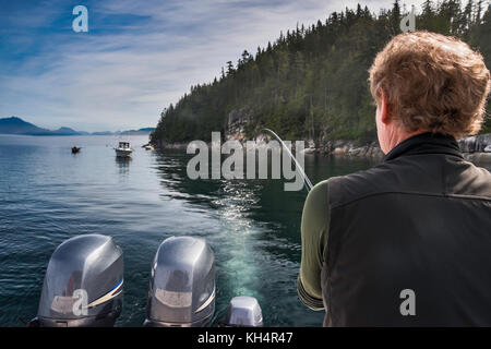 Mann mittleren Alters mit Angelrute auf dem Boot, nebeliger Tag in der Discovery Passage vor Quadra Island, Vancouver Island Area, British Columbia, Kanada Stockfoto