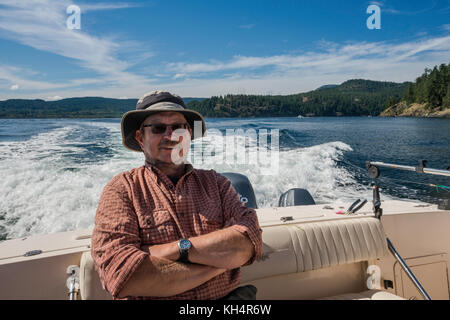 Mann mittleren Alters, der in einem Schnellboot sitzt und von einem Angelausflug zurückkehrt, in der Johnstone Strait vor Vancouver Island, British Columbia, Kanada Stockfoto