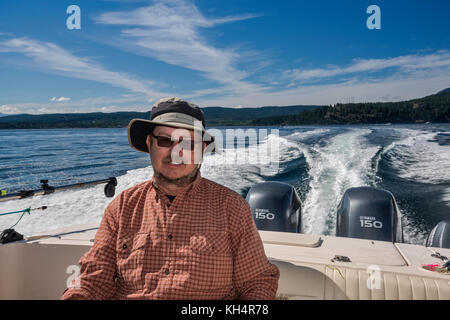 Mann mittleren Alters, der in einem Schnellboot sitzt und von einem Angelausflug zurückkehrt, in der Johnstone Strait vor Vancouver Island, British Columbia, Kanada Stockfoto