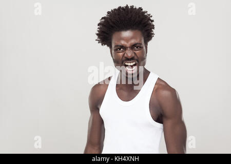 Afro Mann im weißen T-Shirt an Kamera schreien. Studio erschossen. grauer Hintergrund Stockfoto