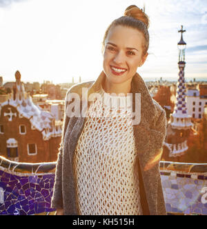 Barcelona Signatur Stil. Portrait von lächelnden trendy Frau im Mantel an Park Güell in Barcelona, Spanien Stockfoto