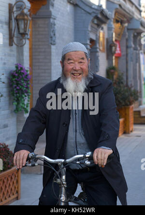 Lächelnd hui muslimischen Mann auf einem Fahrrad auf der Straße, Provinz Gansu, Linxia, China Stockfoto