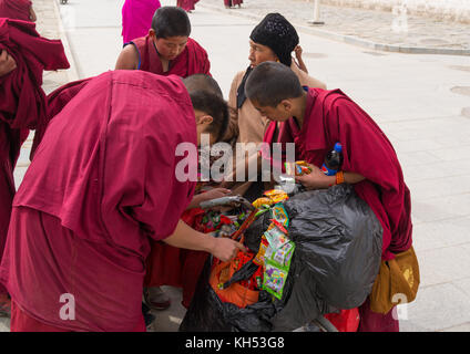 Junge Mönche kaufen Süßigkeiten und Nahrungsmittel zu einem hui Frau Verkäufer, Provinz Gansu, Labrang, China Stockfoto