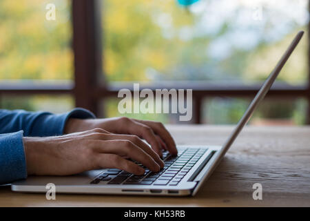 Texteingabe auf einem Laptop vor Fenster auf hölzernen Tisch Stockfoto