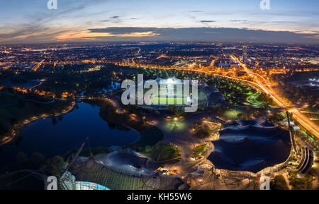 München, Deutschland - 3. November 2017: Panorama des beleuchteten Olympiapark von oben mit leichten Spuren von Datenverkehr bei Sonnenuntergang Stockfoto