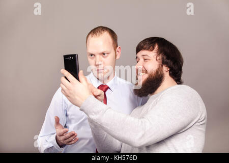 Zwei lächelnde Kollegen der Aufnahme zu Ihnen selbst, glückliche Freunde unter selfie mit Telefon Kamera auf dunklem Hintergrund Stockfoto