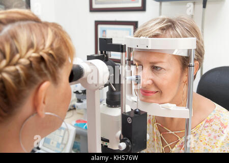 Junge Frau wird von ihr Augenlicht durch Optiker geprüft Stockfoto