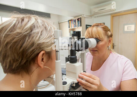 Junge Frau wird von ihr Augenlicht durch Optiker geprüft Stockfoto