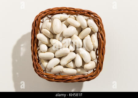 Phaseolus vulgaris ist wissenschaftlicher Name der Marine Bohne Hülsenfrucht. Auch bekannt als weiße, pearl Bean und feijao Branco. Blick von oben auf die Körner in einem Korb. schließen Stockfoto