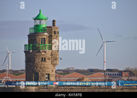 Bremen, 6. November 2017 - Leuchtturm am Hafeneingang mit Industrielagergebäuden und zwei Windkraftanlagen im Backgrou Stockfoto