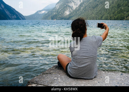 Schöne Mädchen sitzen am See eine selfie Stockfoto