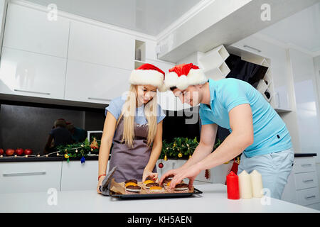 Ein paar in Santa Claus Hüte backen Muffins über Weihnachten in der k Stockfoto