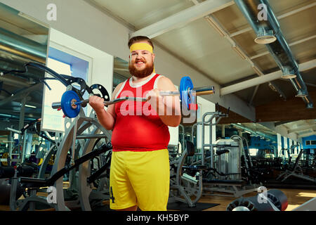 Dicke mann Übungen mit einem barbell in der Turnhalle Stockfoto
