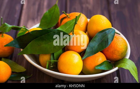 Frische Clementinen Heap mit Blättern auf Holzuntergrund, süßen Bio Mandarine oder clementinen Zitrusfrüchte Stockfoto