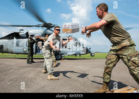 US-Soldaten und Matrosen laden Wasser auf einen US Navy MH-60S Sea Hawk Hubschrauber in Beaumont, Texas, September 3, 2017. Hurrikan Harvey bildete sich im Golf von Mexiko und machte Landfall im Südosten von Texas, was Rekordfluten und Zerstörung in der Region brachte. US-Militärgüter unterstützten die FEMA sowie staatliche und lokale Behörden bei Rettungs- und Hilfsmaßnahmen. (USA Air Force Foto von Tech. Sgt. Larry E. Reid Junior) Stockfoto