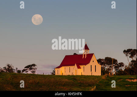 Vollmond hinter einer kleinen Kapelle, Westcoast Northland, North Island, Neuseeland Stockfoto
