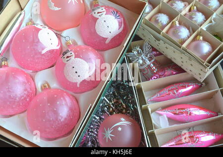 Vintage frosted pink Weihnachtsbaum Kugeln, Dekorationen und Spielereien in alten Kisten auf einem Tisch gestapelt Stockfoto