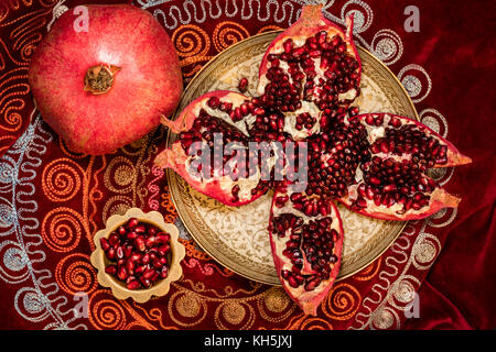 Blick von oben auf die geschälte Granatapfel und Ruby Körner in einer Schüssel auf orientalische Tischdecke Stockfoto