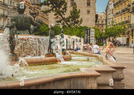 VALENCIA, SPANIEN - 16. Juni 2017 : Touristen sitzen in der Nähe des 1976 eingeweihten Turia-Brunnens, der sich im Zentrum des Virgi-Platzes befindet Stockfoto