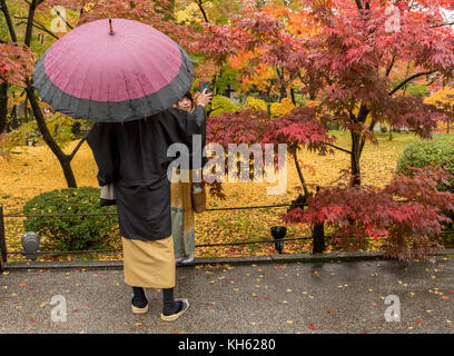 Kyoto, Japan, 14. November 2017: Ein Mann in traditioneller japanischer Kleidung macht Fotos von einer Frau im Eikando-Tempel von Kyoto, einem beliebten Reiseziel, da die Herbstsaison Mitte bis Ende November ihren Höhepunkt in einer kaskadierenden Herbstfarbe erreicht. Quelle: Perry Svensson/Alamy Live News Stockfoto