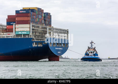 Rotterdam, die Niederlande - Juni 12, 2017: a Tug Boat bringt die extrem großen Containerschiff CMA CGM Bougainville in den Hafen wie es ankommt. Stockfoto