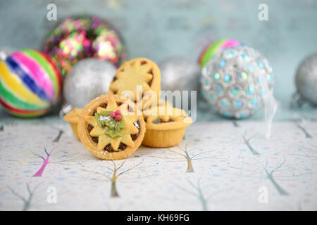 Weihnachten essen Fotografie Bild der traditionellen mince pies mit Baum deko Kugeln in hellen Farben auf glänzenden weißen und hellblauen Hintergrund Stockfoto