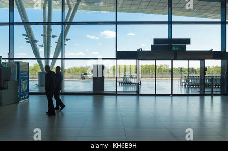 FLUGHAFEN ZAGREB - 24. APRIL 2017: Geschäftsleute gehen vor dem Eingang der Glastür. Stockfoto