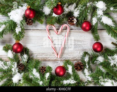 Zuckerstangen mit snowy christmas red Ornamente hängen an Fir Tree Branches Stockfoto