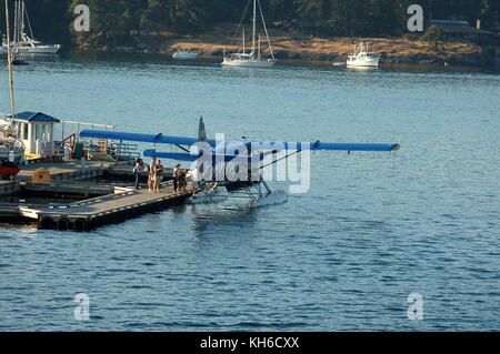 Ein kenmore Air Bayerische Flugzeugwerke Bf DHC-3 Turbine 'Otter' auf Schwimmer, Passagiere laden in Friday Harbor, WA auf dem letzten Flug des Tages. Stockfoto