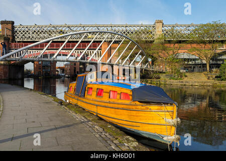 Eine hölzerne Kanal Boot, die 'Lady Avon" (erbaut 1960), die Brücke der Kaufleute und viktorianischen Eisenbahnbrücken in Castlefield, Manchester, UK Stockfoto