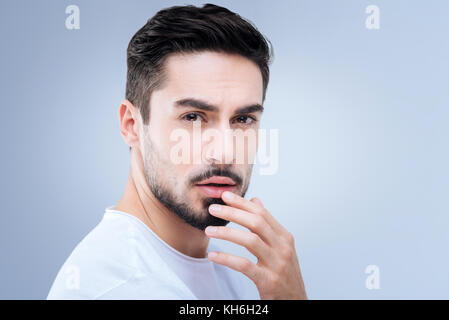 Sensibler Mann berührte seine Lippen, während die Erinnerung an den Kuss einer Freundin Stockfoto