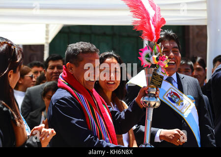 Peruanische Präsident Ollanta Humala hält eine Auszeichnung in Form einer Diablada Tänzer Maske, von seiner Frau Nadine Heredia beobachtet (hinter ihm), Puno, Peru Stockfoto