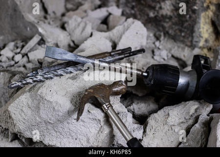 Abriss von Wänden. Elektrische hammer Helm und Gehörschutz liegen auf den Trümmern. alte Ziegel und renovierten Gebäude Wand. Grunzen auf dem Hintergrund Stockfoto