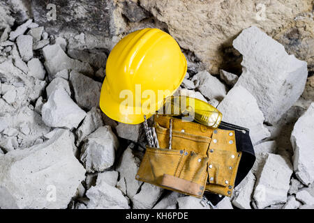 Abriss von Wänden. Elektrische hammer Helm und Gehörschutz liegen auf den Trümmern. alte Ziegel und renovierten Gebäude Wand. Grunzen auf dem Hintergrund Stockfoto