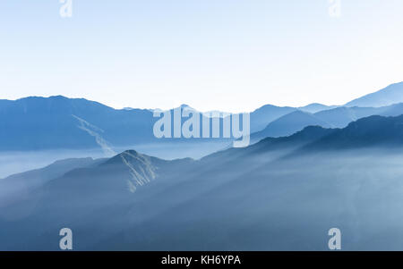 Dunstig blauen Berge von zhushan in alishan Erholungsgebiet in Taiwan durch Nebel bei Sonnenaufgang am Morgen bedeckt mit hellen Himmel. Stockfoto