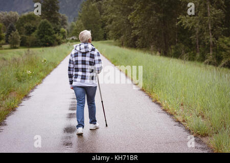 Ältere Frau Wanderer wandern mit Wanderstöcken im Wald Stockfoto