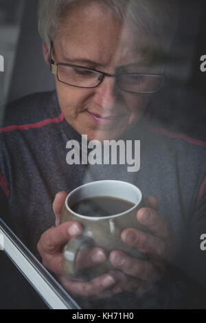 Ältere Frau mit Tasse Kaffee zu Hause Stockfoto