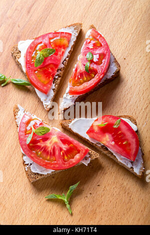 Sommer Sandwiches mit Tomaten und Basilikum auf einer hölzernen Oberfläche. Stockfoto