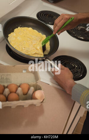 Der Mensch bereitet Rührei in die Pfanne in der Küche Stockfoto