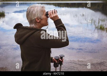 Ältere Frau Wanderer durch ein Fernglas im Wald suchen Stockfoto