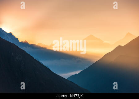 Majestätischen Blick auf die Silhouetten der Berge und niedrige Wolken bei Bunte sunrise in Nepal. Landschaft mit schneebedeckten Gipfel der Berge des Himalaja, schöne Sk Stockfoto