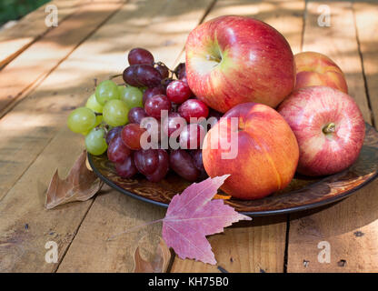 Platte der Äpfel, Pfirsiche und Trauben auf einer hölzernen Oberfläche Stockfoto