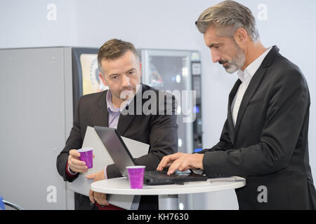 Männer mit Laptop von Verkaufsautomaten Stockfoto