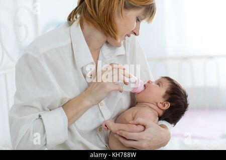 Mom-Holding und Wasser zu Baby Kleinkind von der Flasche Stockfoto