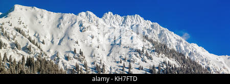 Hohe Berge mit Gipfelkreuz unter tiefen Schnee im Winter. rauhhorn, Allgäu, Bayern in Deutschland. Stockfoto