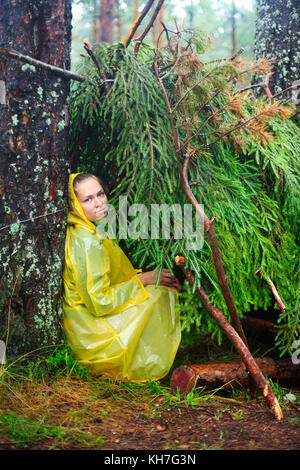 Junge Frau tragen gelbe Regenjacke sitzen in einem Tierheim von Zweigniederlassungen Stockfoto