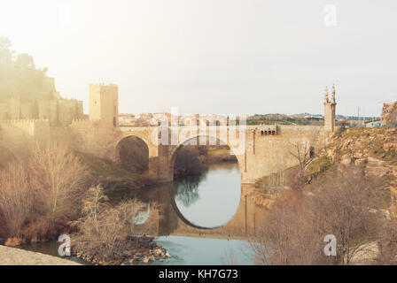 Ein Bogen alcantara Brücke über den Fluss Tejo und seine Reflexion im Wasser im Winter abends Tag, Toledo. Stockfoto