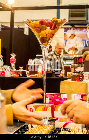 Handwerkliche Spezialitäten in einem riesen Martini Glas Display mit einem Verkäufer Übergabe Einkäufe, Salon Chocolat & Gourmandises, Toulouse, Royal, Frankreich Stockfoto