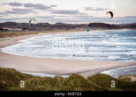 Kitesurfen Männer in Aktion an stürmischen Sonnenuntergang Abend in brusand Strand, Norwegen. Stockfoto